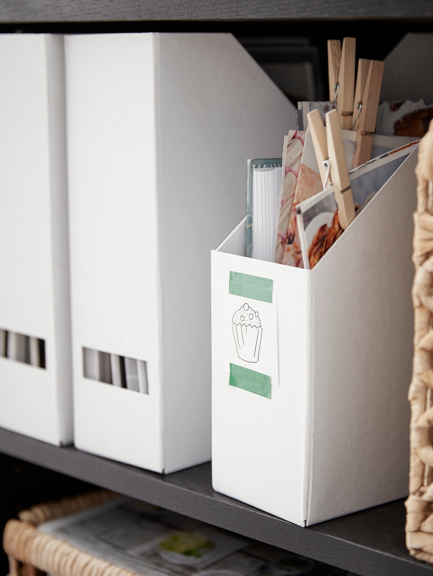 Three TJENA magazine files in a bookshelf and one with recipes and a baking sticker on the front of it
