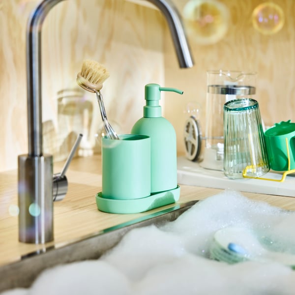 Dispenser per sapone, portaspazzolino e vassoio in gres verde GANSJÖN vicino al lavello in una cucina Scandinavian Modern.
