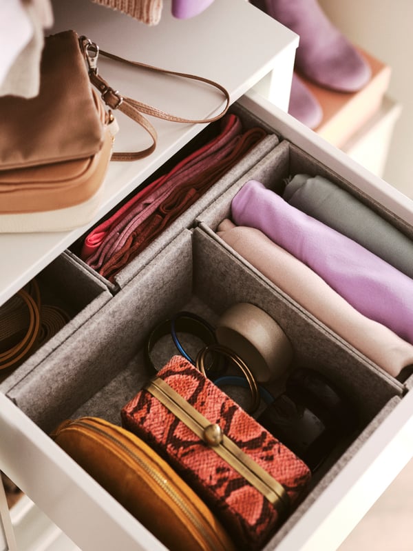 A drawer in a PAX wardrobe is open. Inside it, there are KOMPLEMENT boxes containing folded clothes and accessories.
