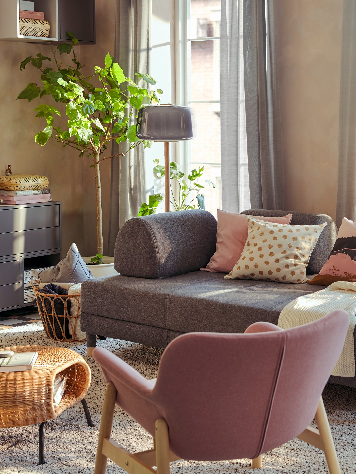 Una sala con un sofá FLOTTEBO y un sillón VEDBO rosa.