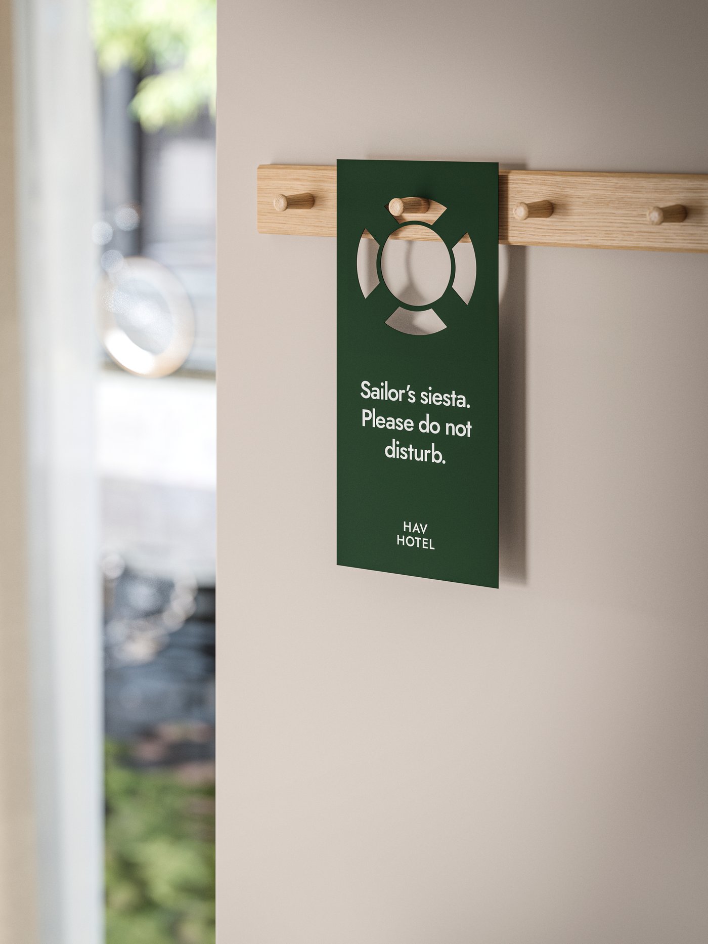 A beige wall in a houseboat hotel room with HÖVOLM racks with six knobs and a do not disturb sign with a sailing theme.