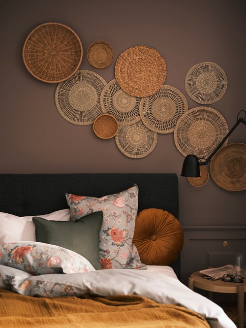Close-up on bedroom with cosy bed and wall decorative art made of set of 3 woven sedge wall decorations, and place mat.
