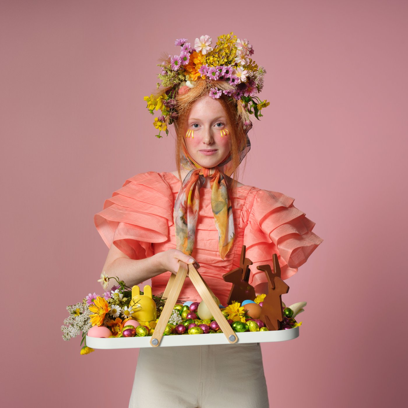 Woman dressed in Easter outfit holding platter with fruits and chocolate