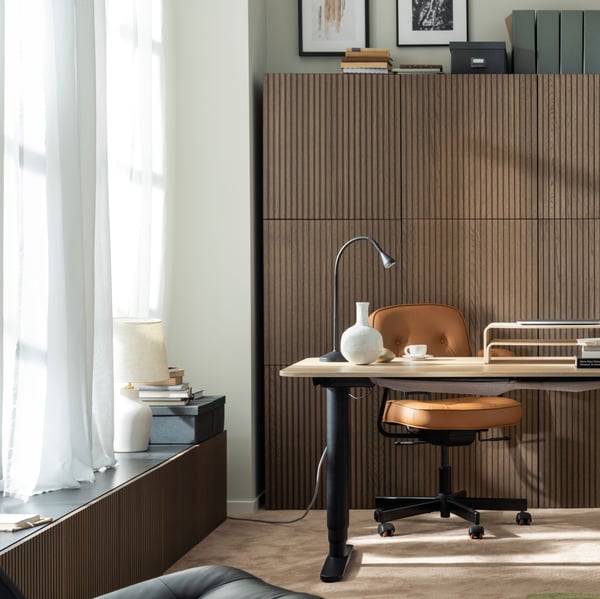 Móvel de TV BESTÅ e combinação de arrumação BESTÅ ambos com portas BJÖRKÖVIKEN no canto de sala, junto a secretária.