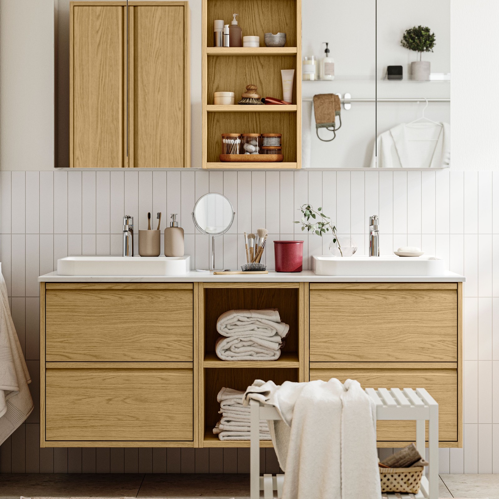A bright bathroom has ÄNGSJÖN bathroom furniture in oak effect, including wall cabinets and a wash-stand with drawers.