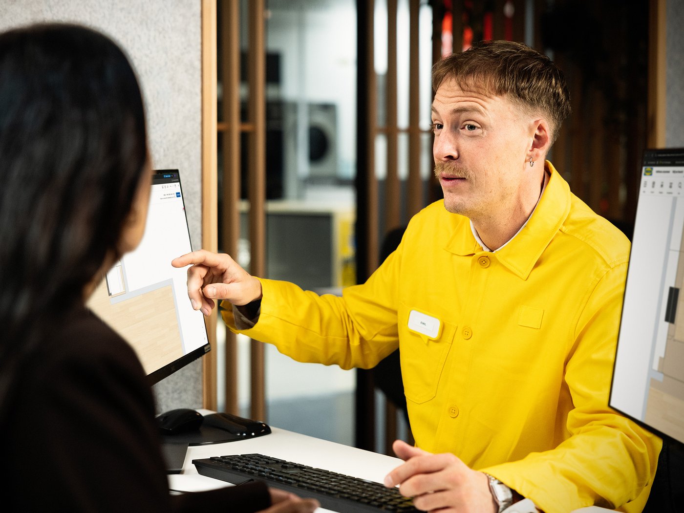Een IKEA medewerker toont een 3D-ontwerp van een keuken aan een klant.