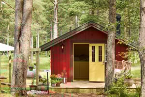 A long shot of a red cottage with a pale yellow door