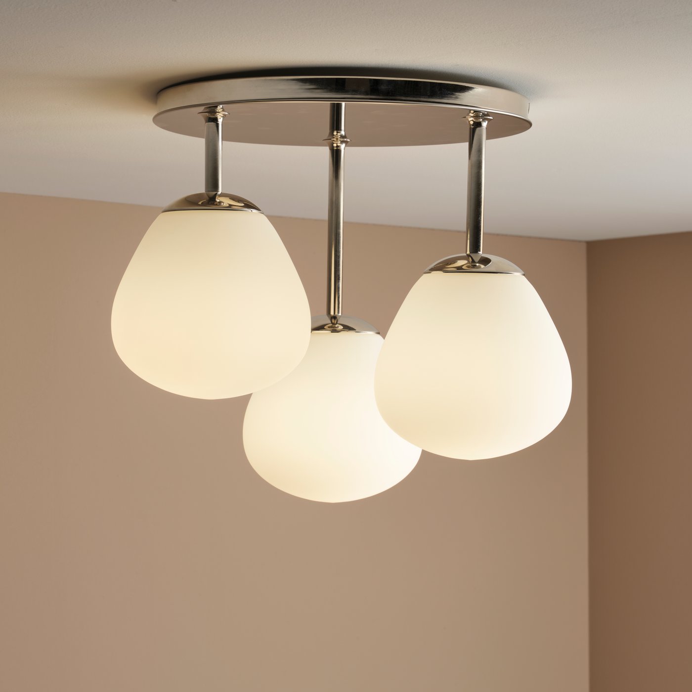 A chrome-plated/opal white glass DEJSA ceiling lamp with 3 lamps is attached to a white ceiling in a room with beige walls.