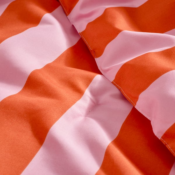 Es ist eine gefaltete IKEA Decke in Orange und Rosa zu sehen.