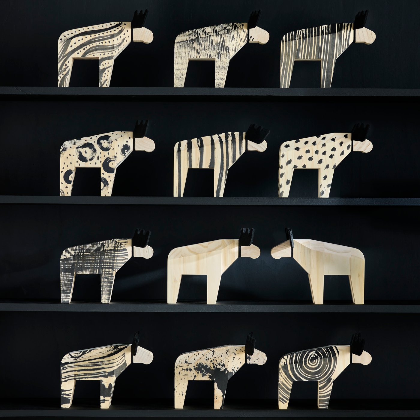 Dvanáct dekorací HÖSTAGILLE s losy je vystaveno na policích, tři na každé polici. Některé jsou částečně natřeny na černo.