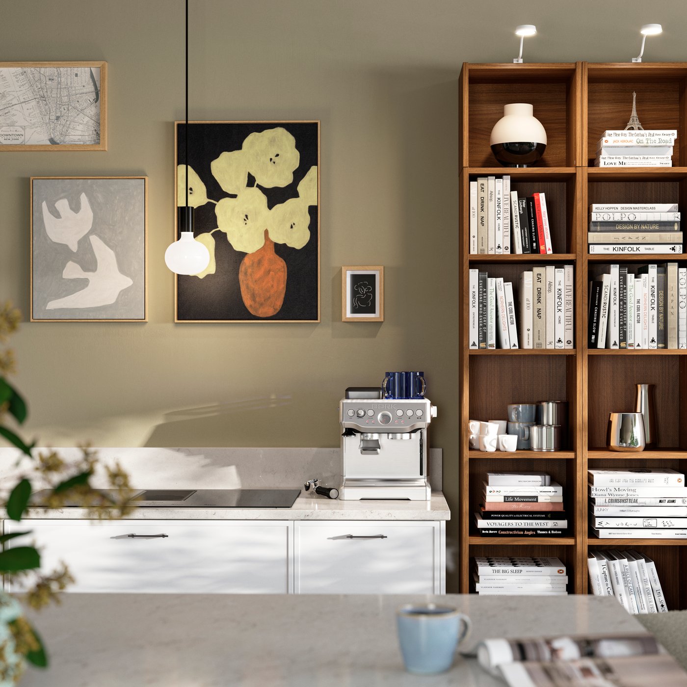 Une cuisine dont les murs sont ornés de tableaux, dont celui intitulé « BLODFLÄDER », à côté d'une bibliothèque en bois remplie de livres et d'objets décoratifs.