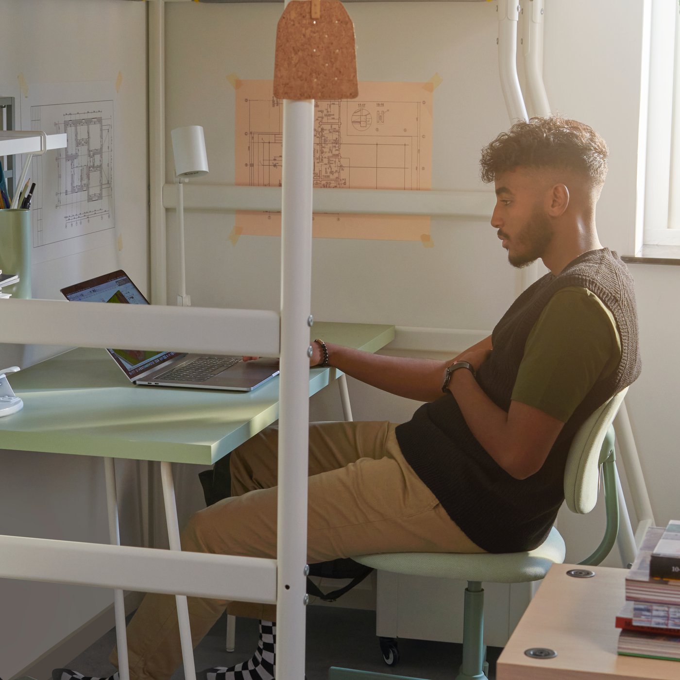 Studente seduto a una scrivania LAGKAPTEN/TILLSLAG su una sedia girevole BLECKBERGET, sotto un letto a soppalco VITVAL.