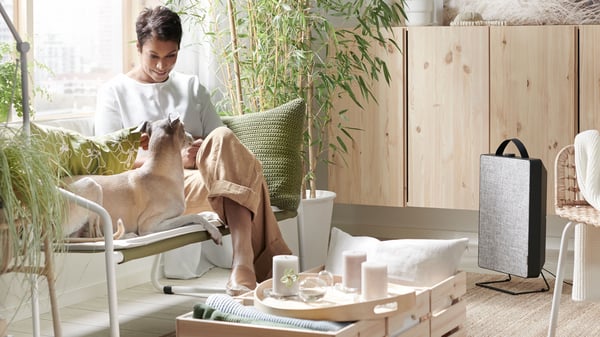 a living room with a lady sitting on a bench petting  her dog
