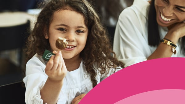 Una bambina seduta ad un tavolo che osserva una polpetta. 