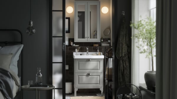 A small traditional-style bathroom with TÄNNFORSEN storage furniture, round lamps and black details.
