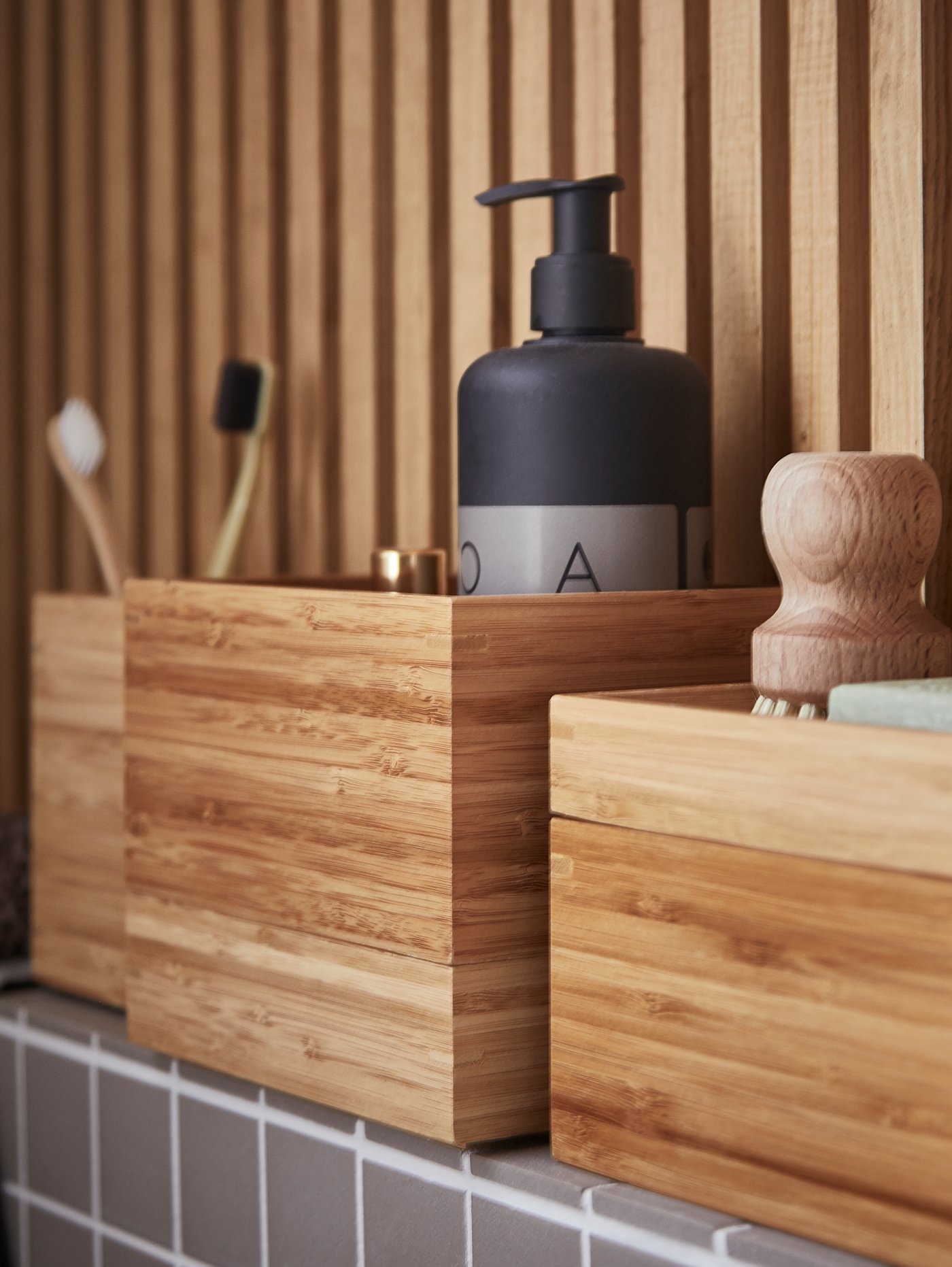 Ett DRAGAN badrumsset med fyra badrum i bambu med produkter som tandborstar i står på en avsats.