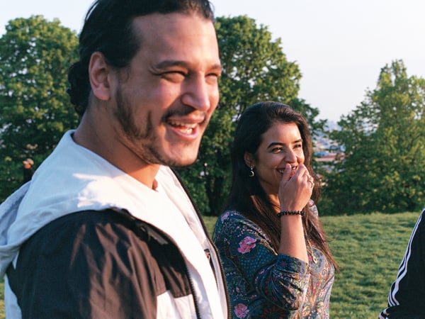 Two people walking outside in a green park, laughing and smiling together.
