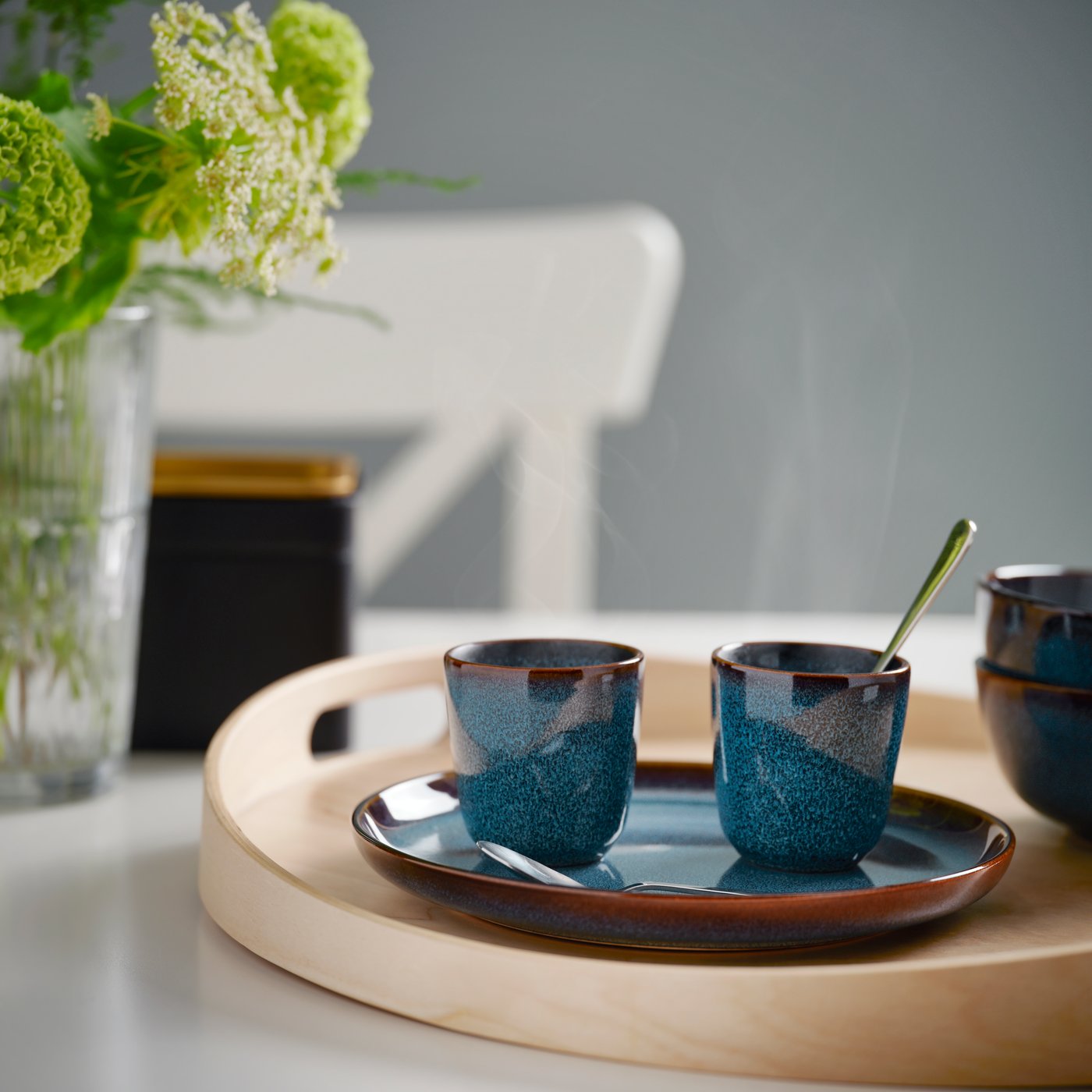 Due tazzine blu GLADELIG con cucchiaino da caffè su un vassoio in legno