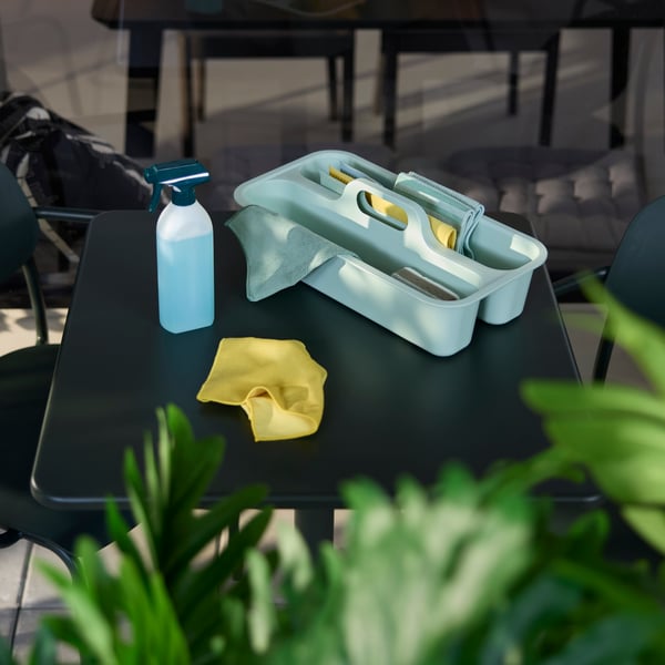 A table counter displays a green PEPPRIG cleaning bucket and caddy together with a spray bottle and cloth beside it.