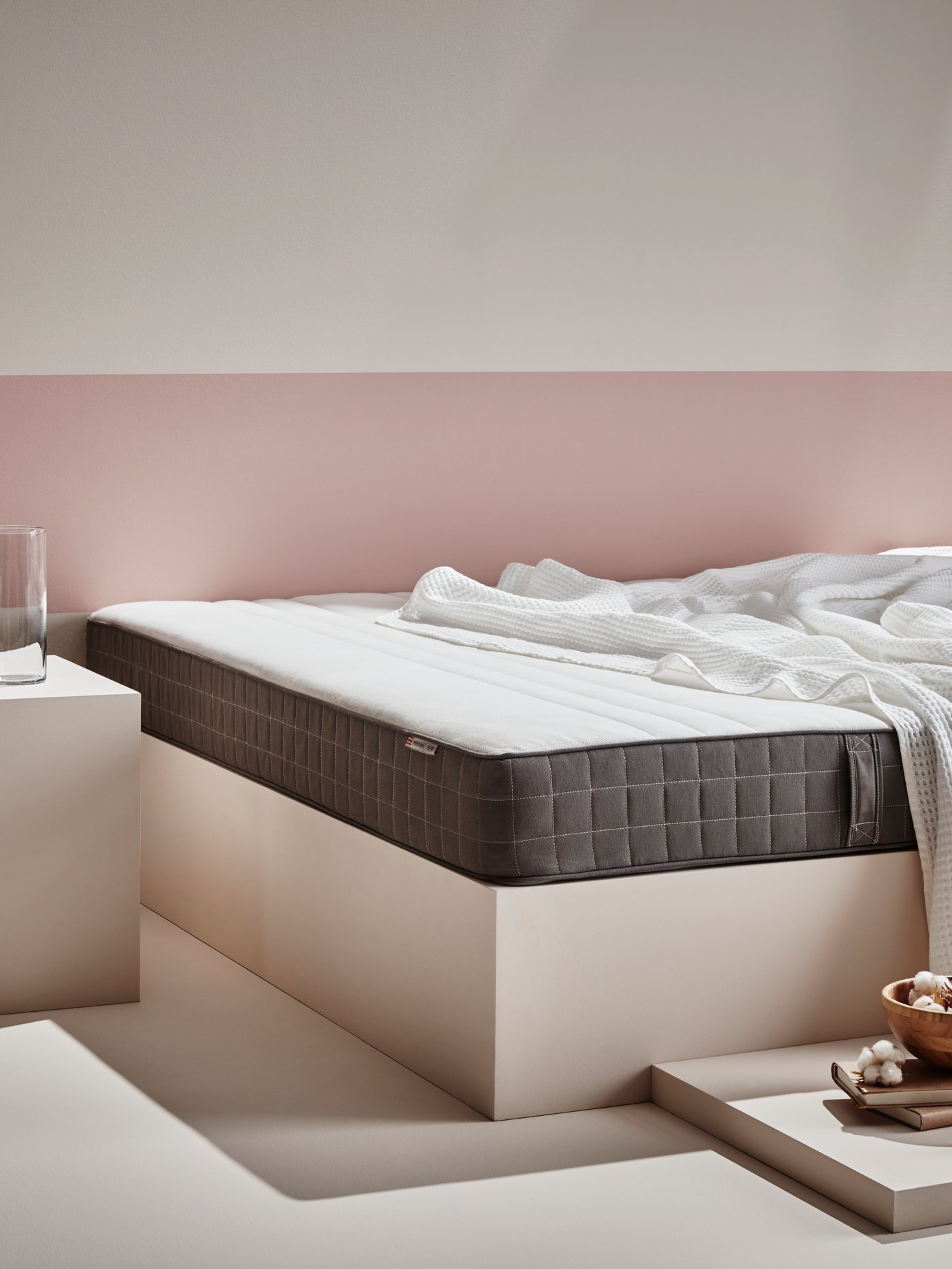 Matras wat op een wit bedframe ligt.