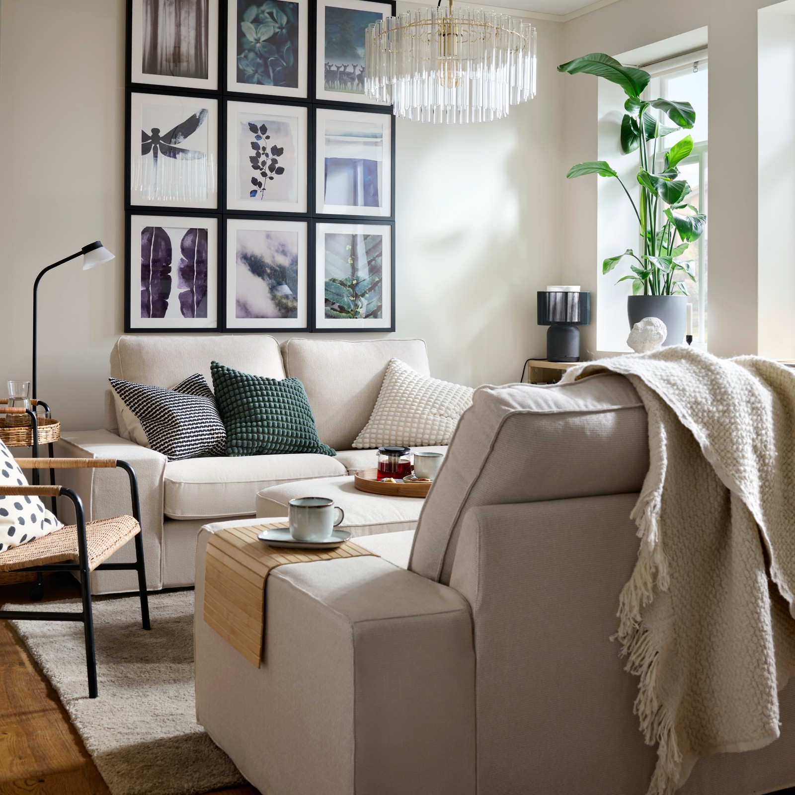 Unha sala de estar luminosa cunha distribución simétrica de cadros na parede en fronte de sofás de dúas prazas KIVIK con coxíns de cores.