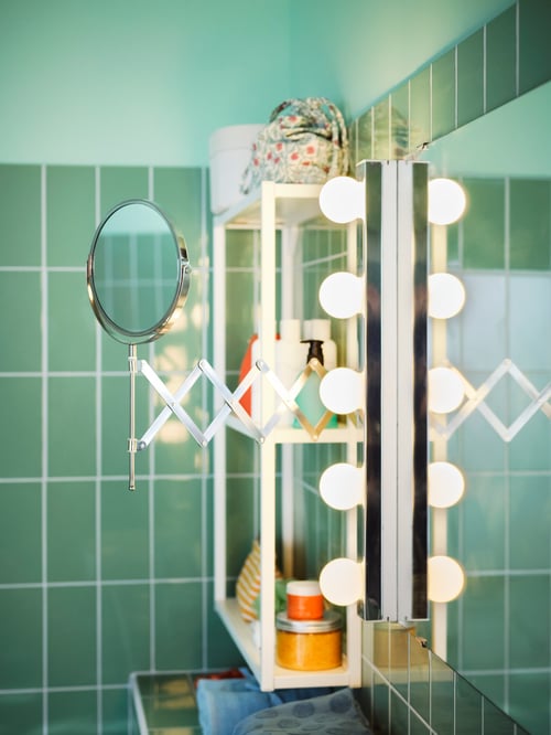 A mirror with a LEDSJÖ led wall lamp with five bulbs and a small magnifying FRÄCK mirror on the side in a green bathroom.
