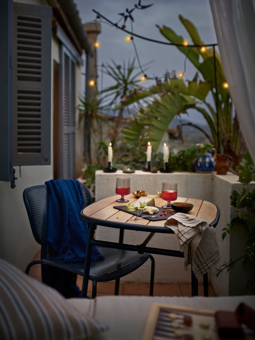 Dining space featuring a rectangular DUVSKÄR table for outdoor supporting 2 grey OMBONAD goblets and a VÅRARV placemat.