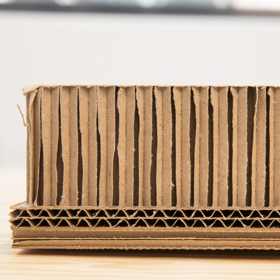 A close-up of a cut brown paper-based pallet showing corrugated layers with different compositions.