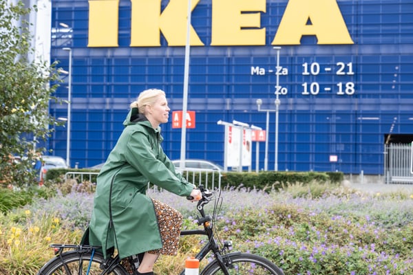 A girl riding a bike with an IKEA store in the background