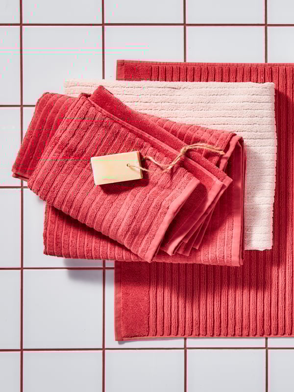 An image of towels lying on top of each other in the color red against a white background.
