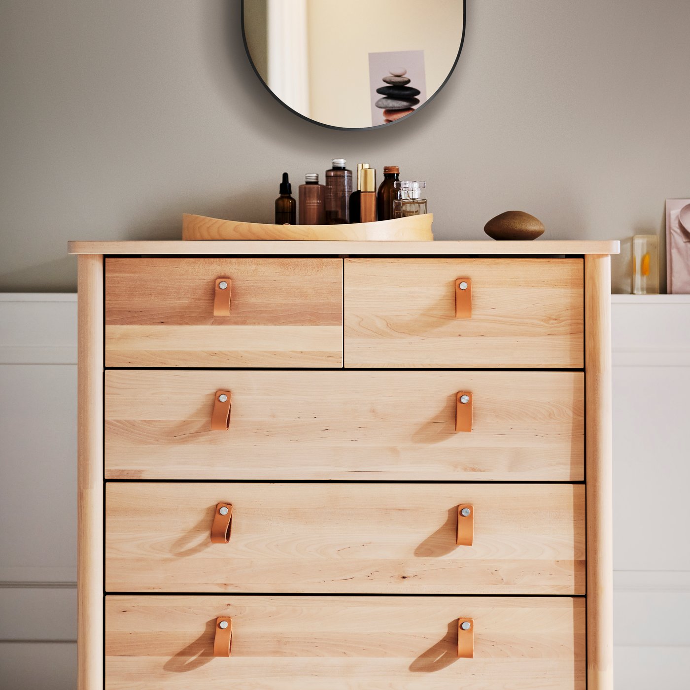 Březový SKALA podtácek na dřevěné komodě s koženými úchytkami.