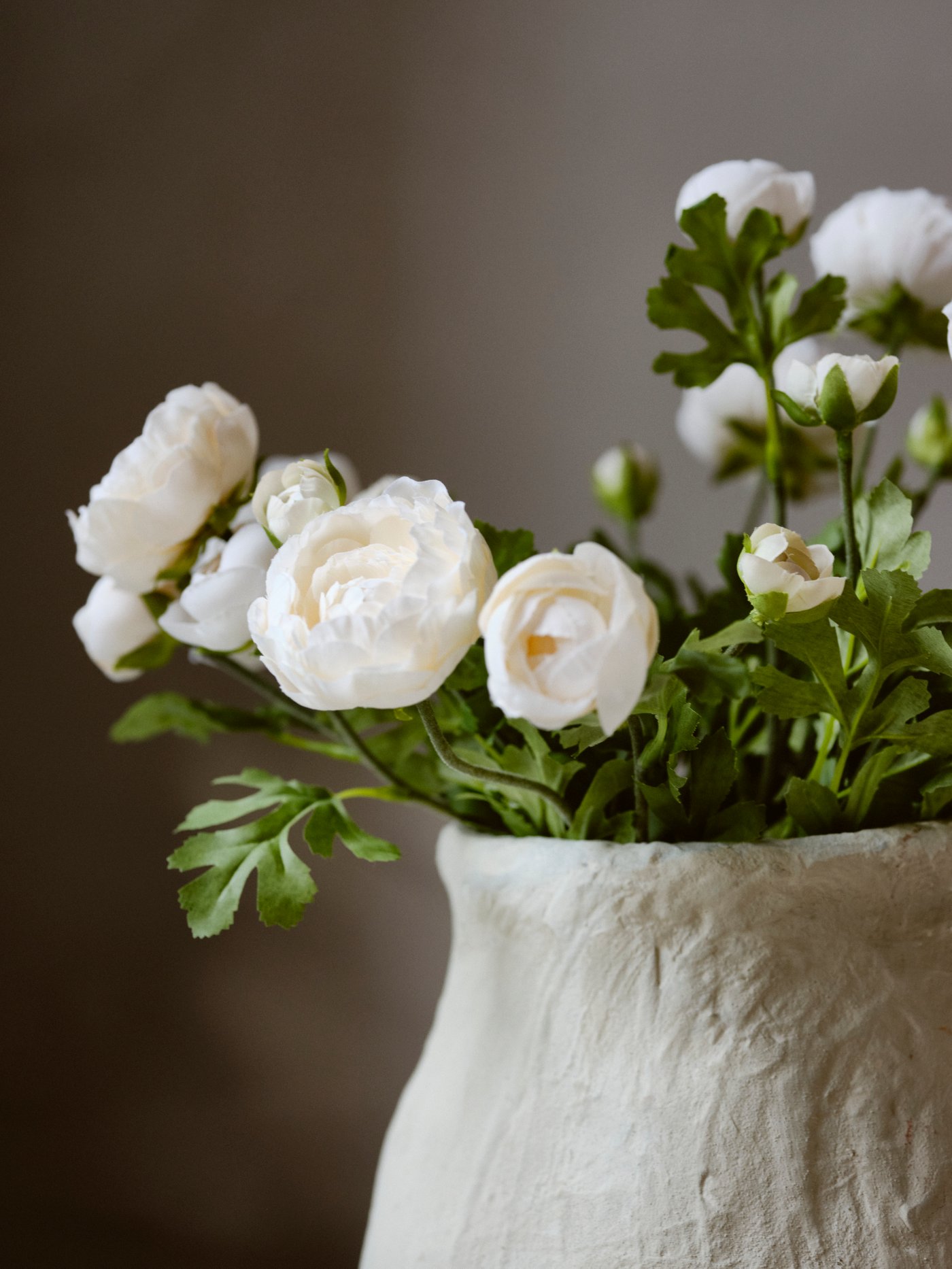 Floral arrangement being created with greenery and white flowers.