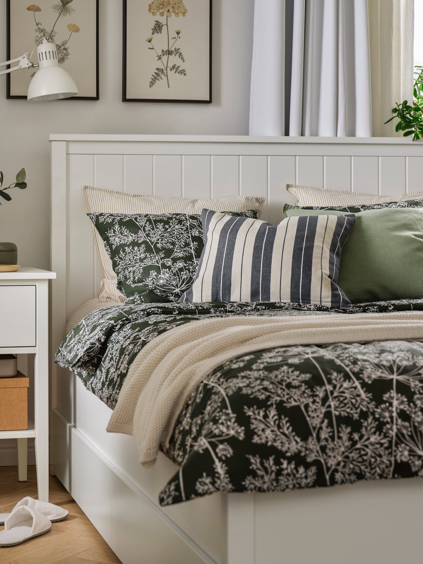 A cosy bedroom with a GULLABERG bedside table and bed frame. DAGGBJÖRNBÄR bed linen is on the bed with cushions and a throw.
