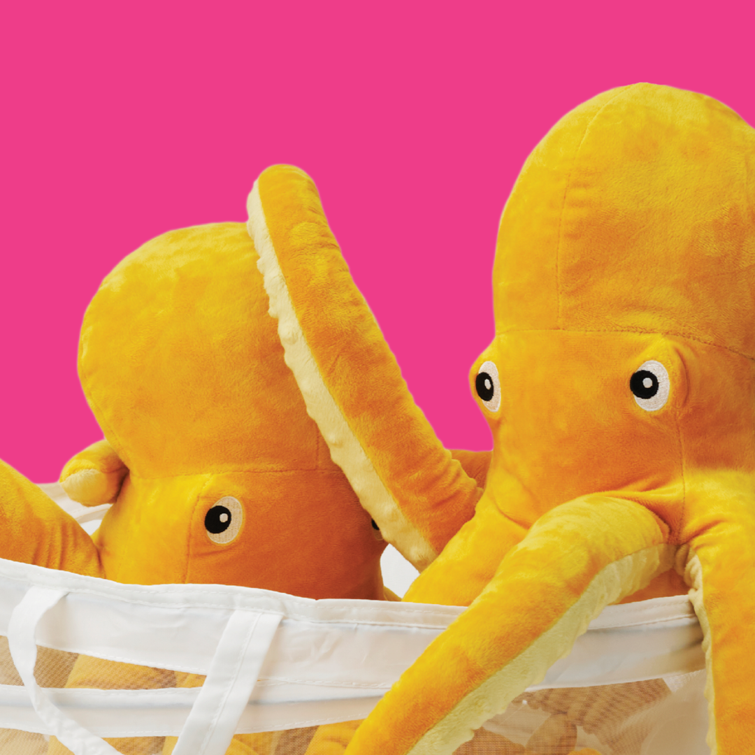 To gule blæksprutte bamser er sat ned i et beige net på en pink baggrund.