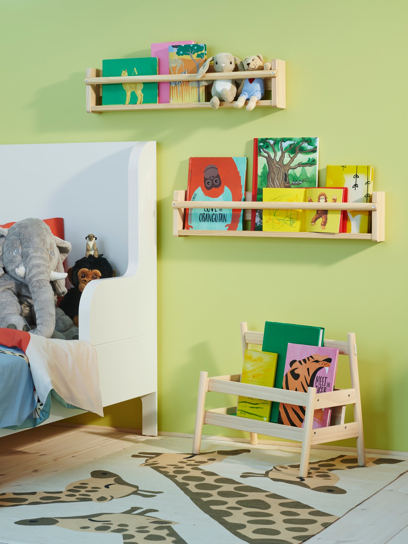 A FLISAT book display on the floor and two FLISAT wall storage on the wall in a colourful children’s room by a white bed.
