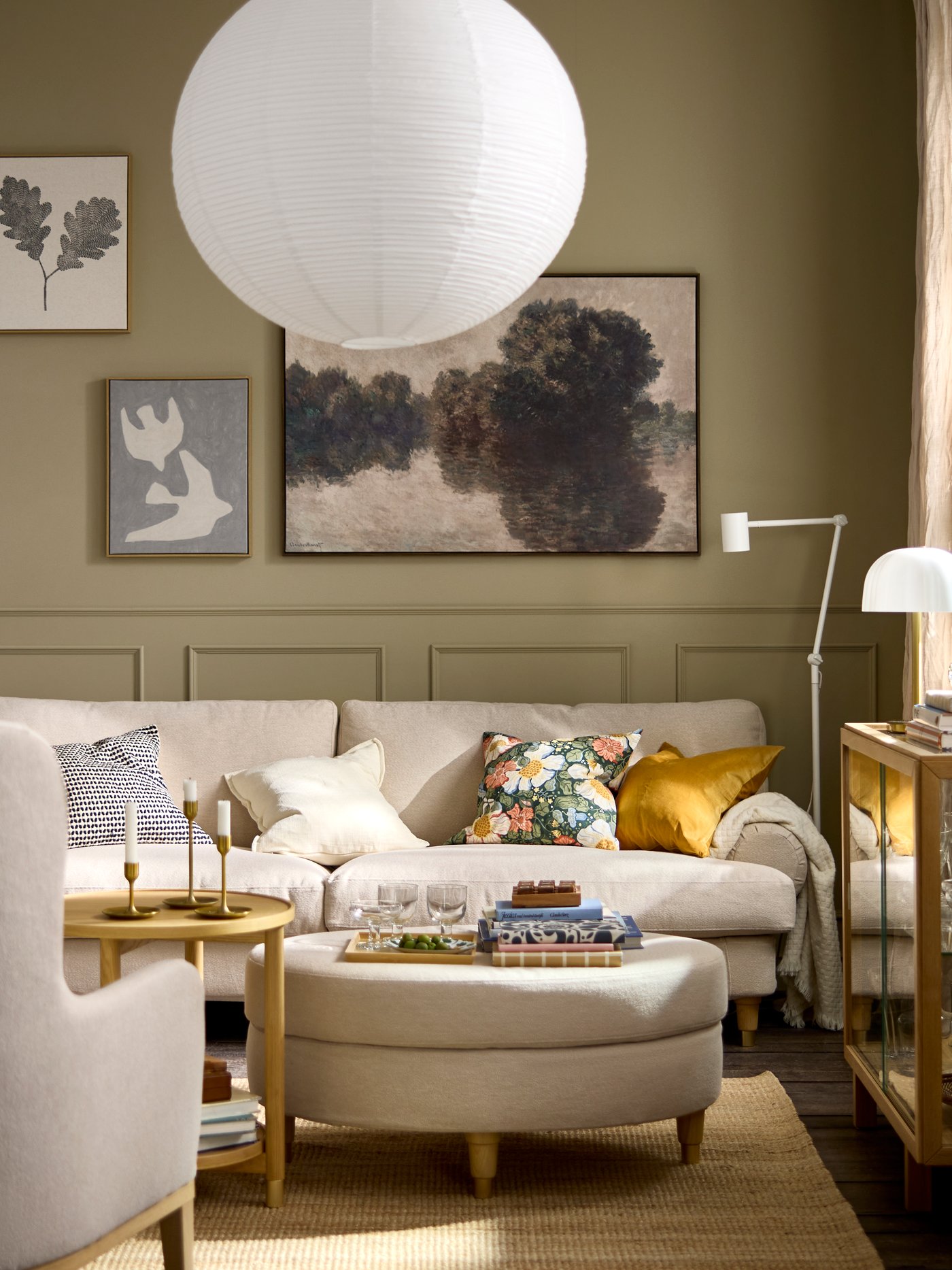 A living room with a light-beige VALNÄS sofa dotted with colourful cushions, a round VALNÄS footstool acting as coffee table.