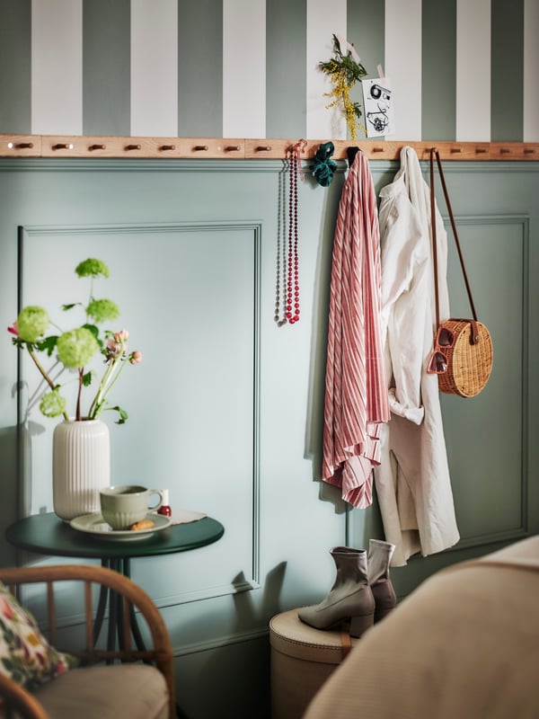 Eine Wand in Pastellgrün, mit Inneneinrichtung in sanften Tönen.