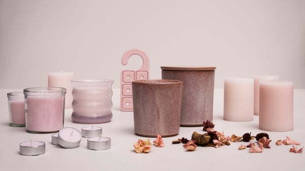 A display of LUGNARE jasmine scented candles, potpourri and a scented hanger against a light pink background.