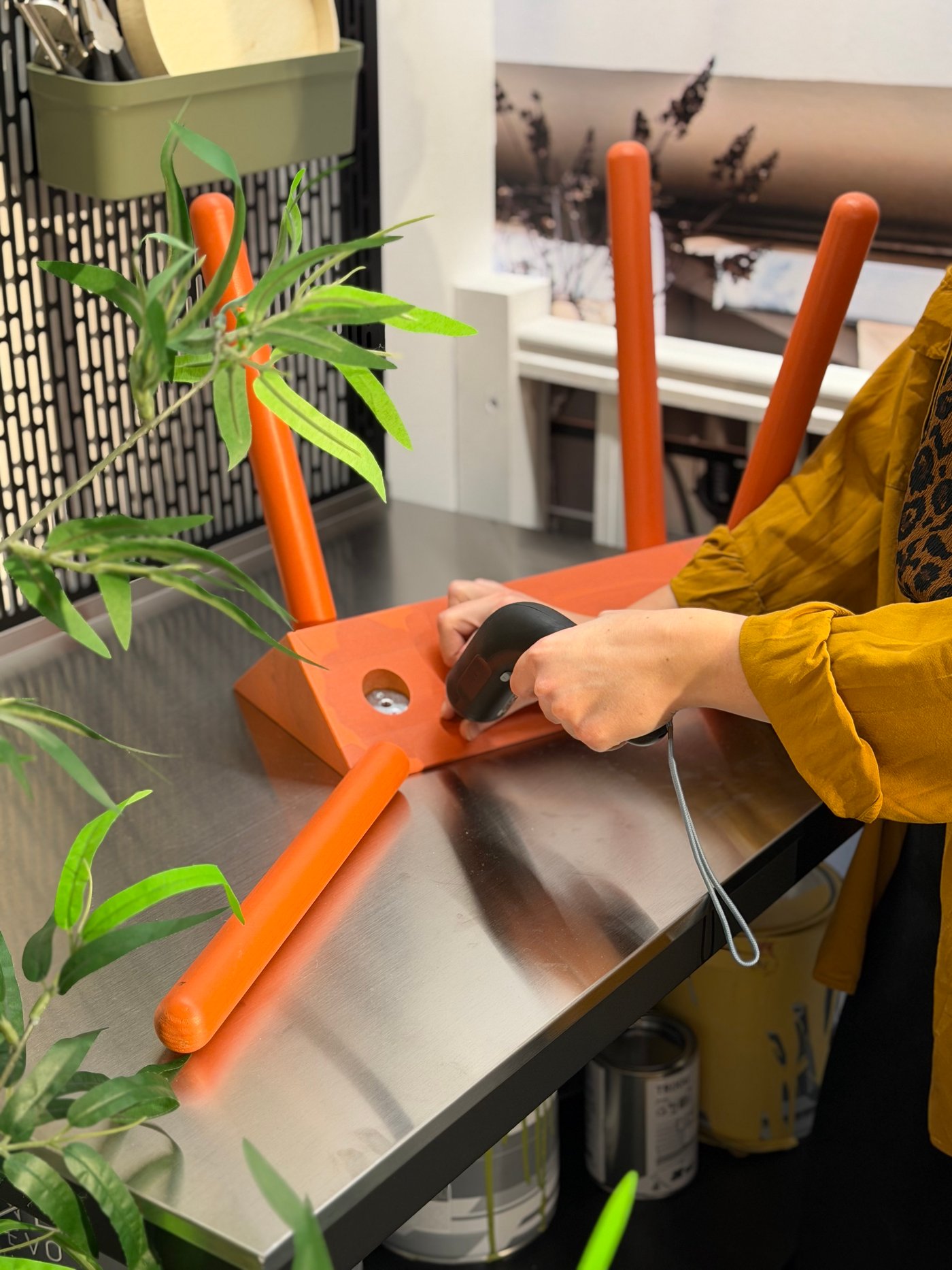 Une main tenant une visseuse et un meuble orange