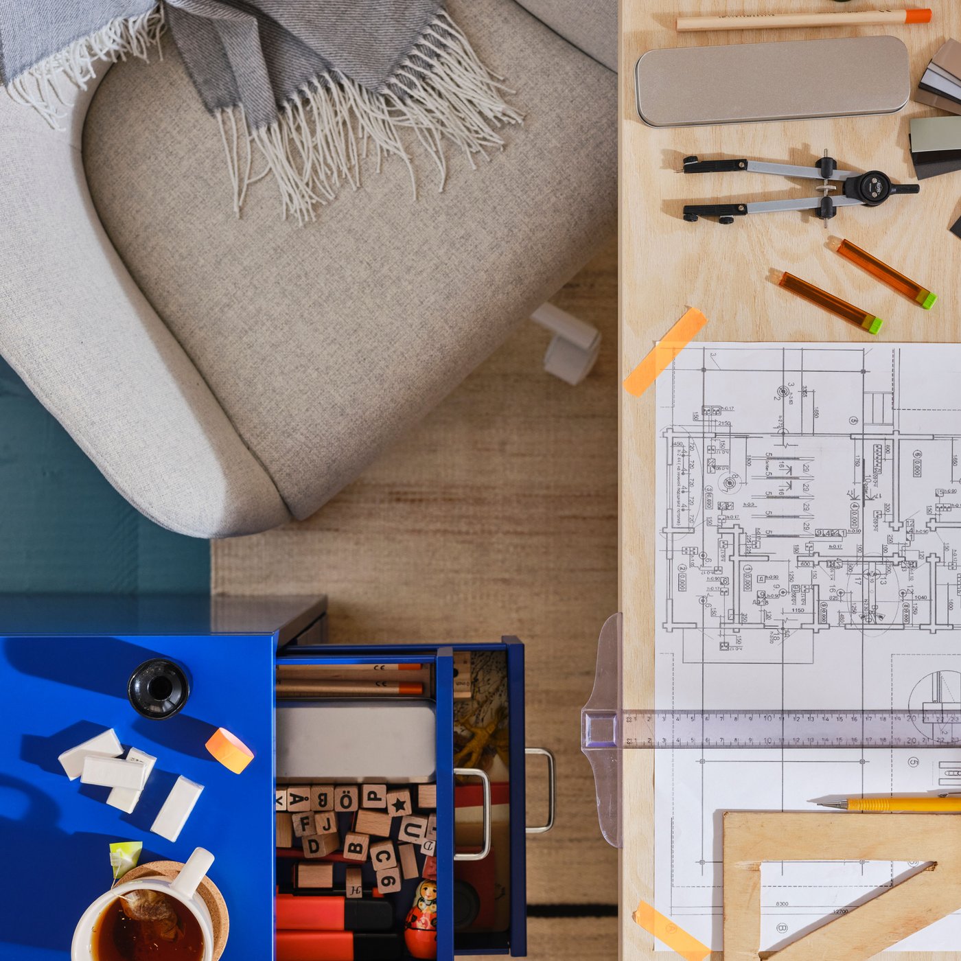 وحدة درج HELMER زرقاء على عجلات أمام طاولة بها رسومات فنية، بواسطة كرسي دوار TOSSBERG/ MALSKÄR.