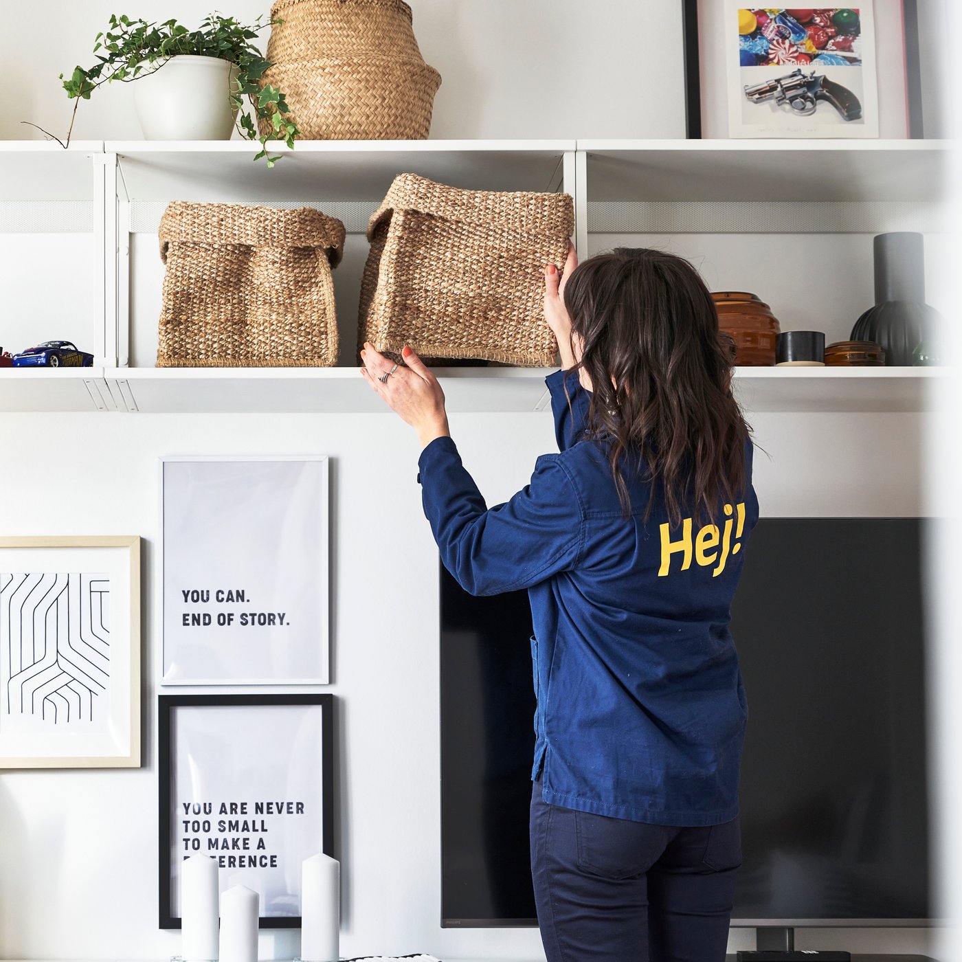 Inredare från IKEA sätter in en korg i en vit hylla.
