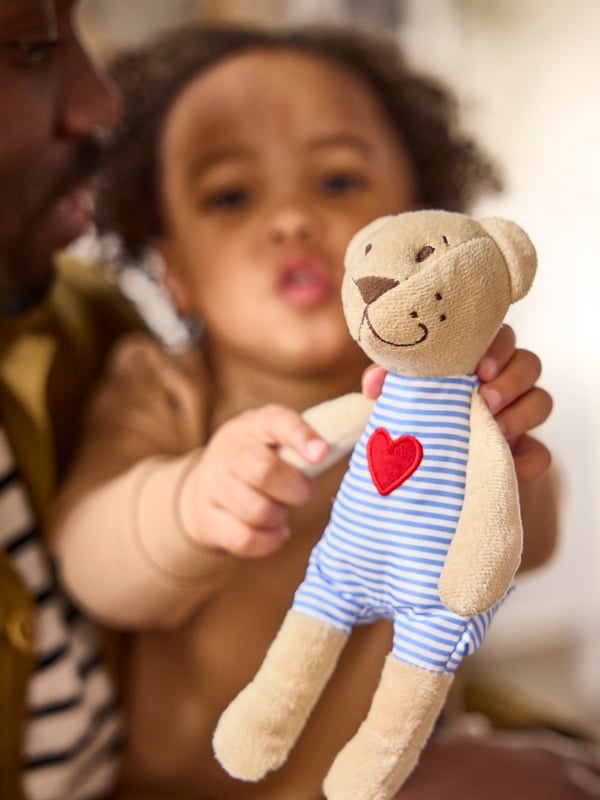 Un niño con un peluche FABLER BJÖRN en las manos mientras su padre lo abraza.