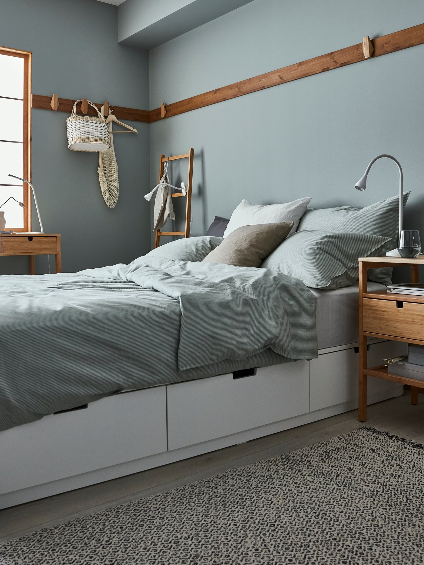 Dormitorio moderno con estructura de cama con seis cajones de cierre suave, una mesilla de noche, una funda nórdica, una alfombra y una lámpara de trabajo LED. 