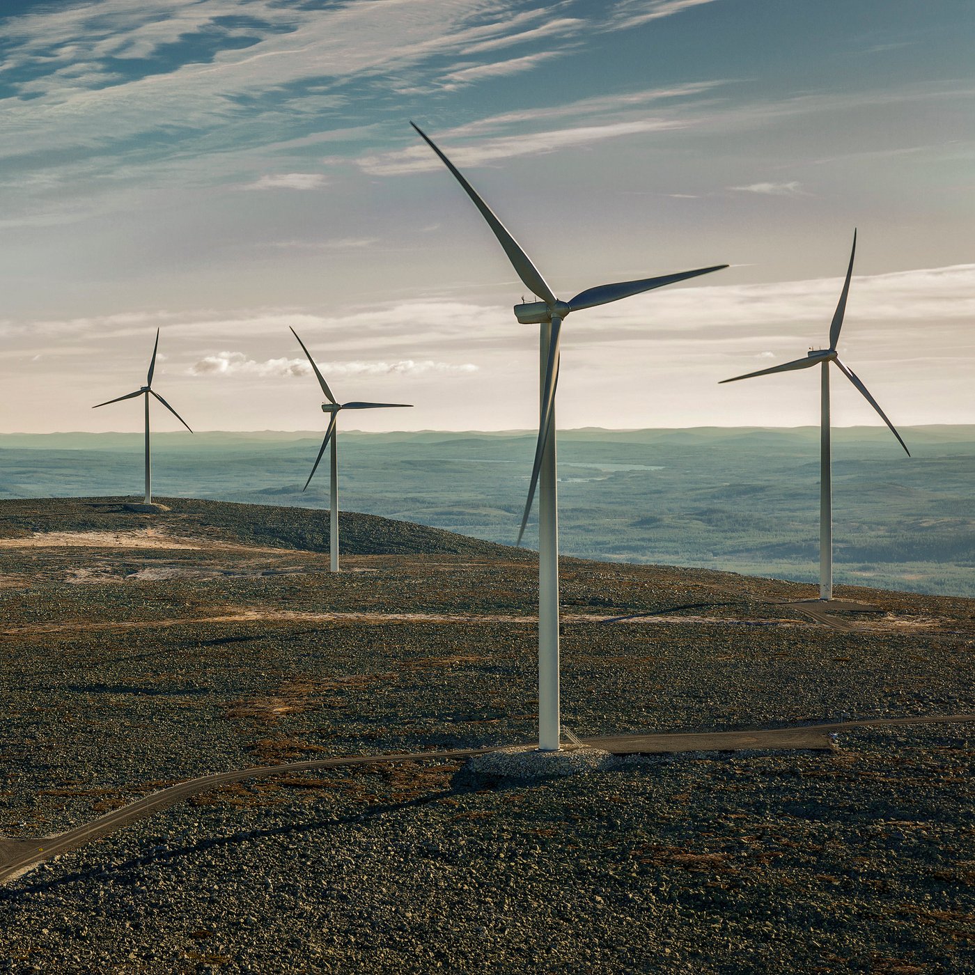 Fünf Windräder stehen auf einem kargen Hügel unter einem bewölkten Himmel und nutzen die erneuerbare Energie des Windes.