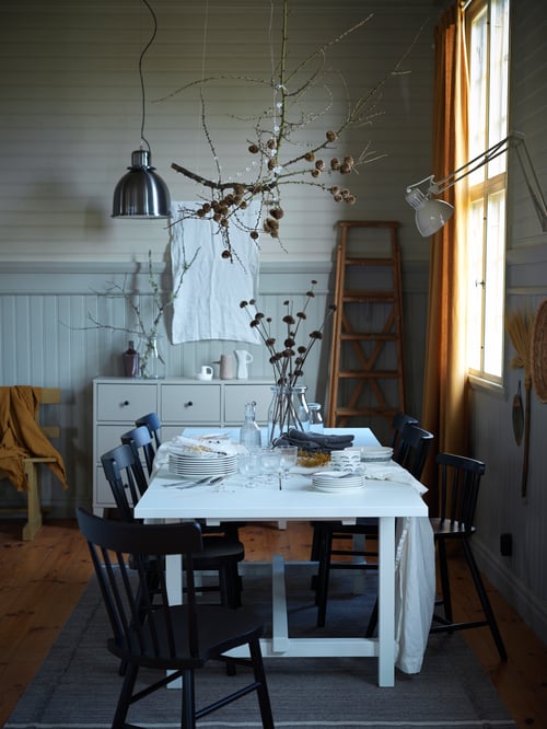 Ein weißer NORDVIKEN Ausziehtisch steht hier in einem rustikal gestalteten Esszimmer. Er ist mit einfachem Geschirr und Glaswaren gedeckt.