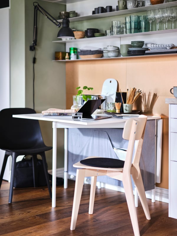 An anthracite ODGER chair and ash LISABO chair at a KALLHÄLL gateleg table with storage, set up as a workspace with a laptop.