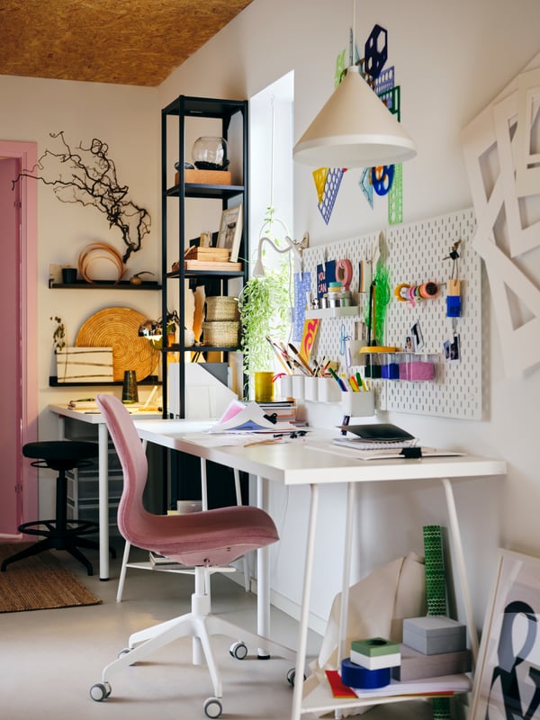 In einem Teenager-Zimmer ist ein weißer Schreibtisch mit rosa Stuhl im Zentrum zu sehen.