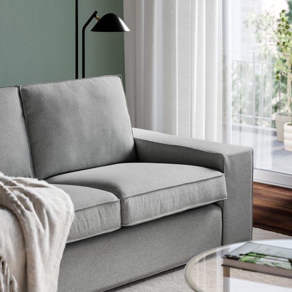Närbild på en grå KIVIK 2-sits soffa stående vid fönster i run med gröna väggar,