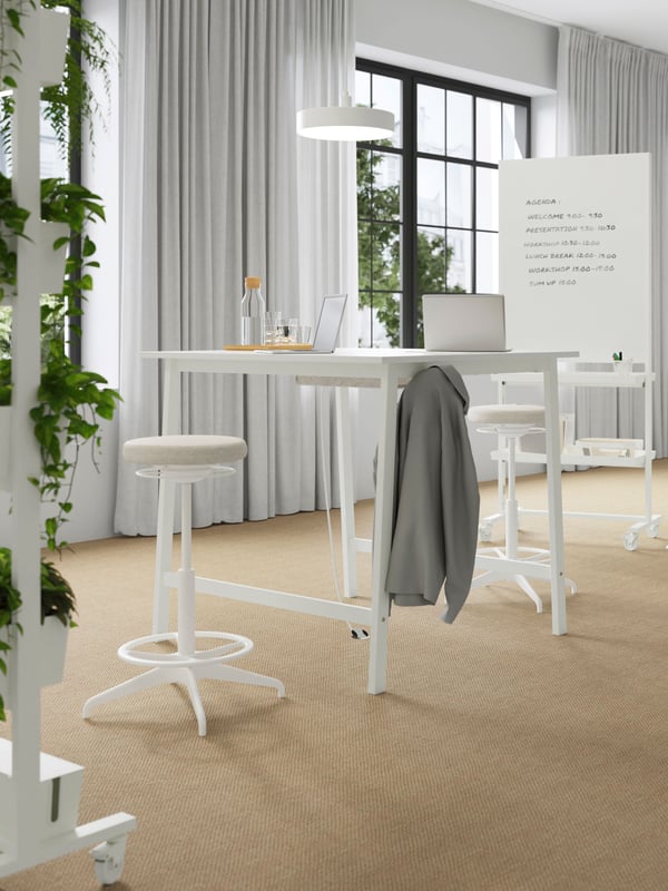 An open-plan office with two MITTZON frames with castors with notes and drawings are placed next to a table with a laptop.