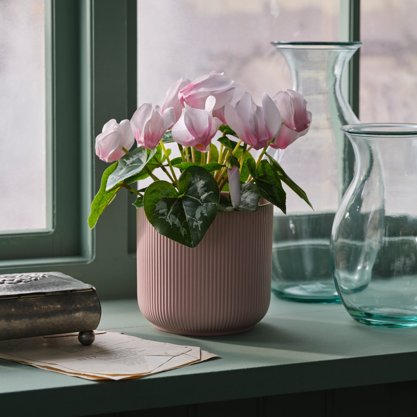 Un cache-pot HONUNGSPALM pour l’intérieur et l’extérieur, aux couleurs assorties, sur le rebord d’une fenêtre
